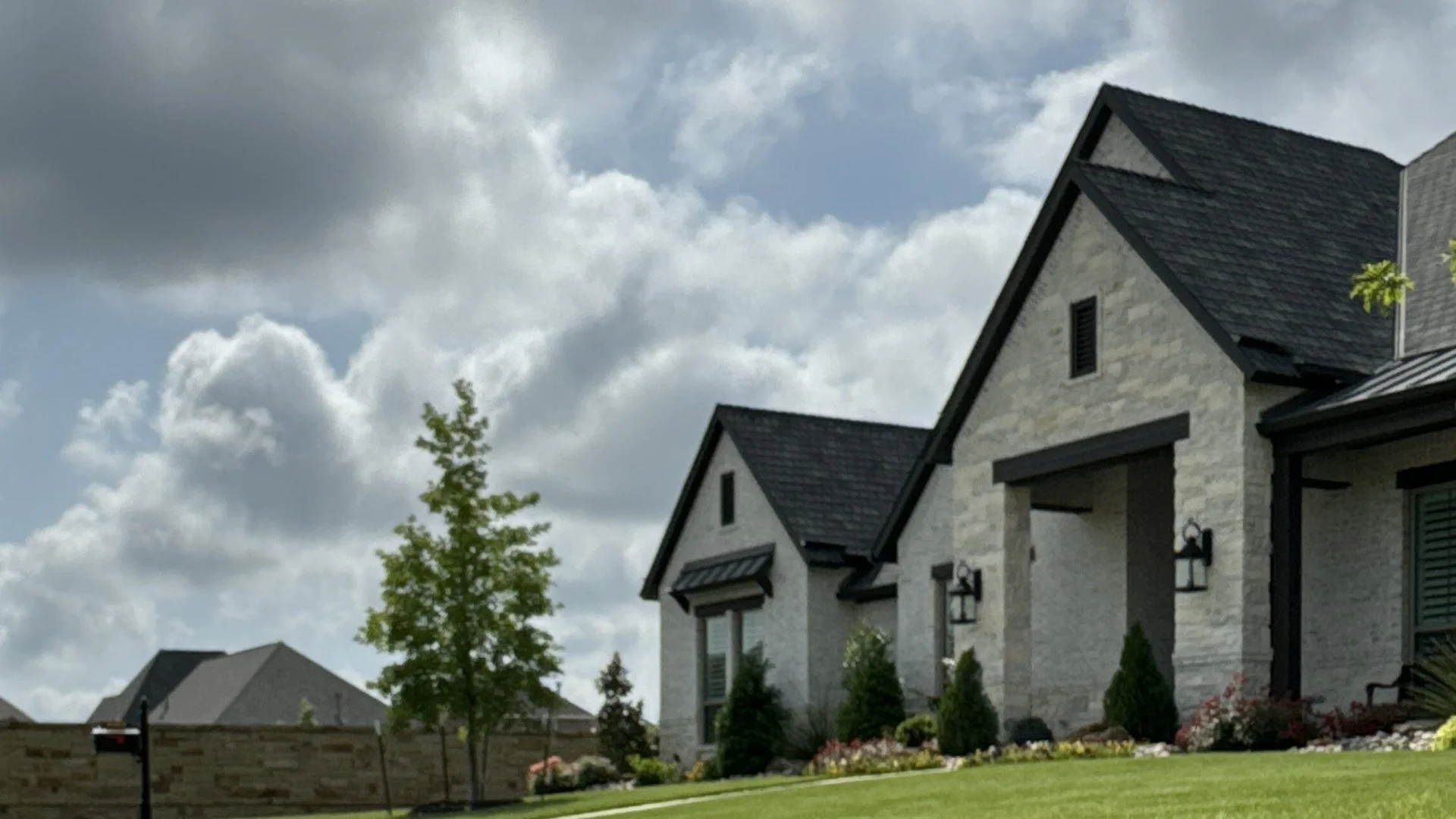 House with tree, shrubs, green lawn in Rowlett, TX.