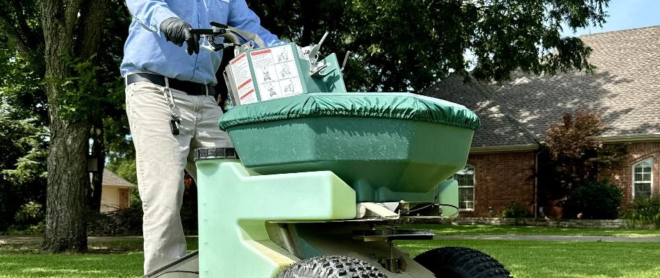 Crew operating a spreader machine of fertilizer treatment for a lawn in University Park, TX.