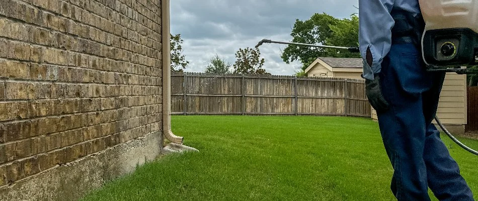 Liquid perimeter pest control treatment being applied to the side of a home in Dallas, TX.