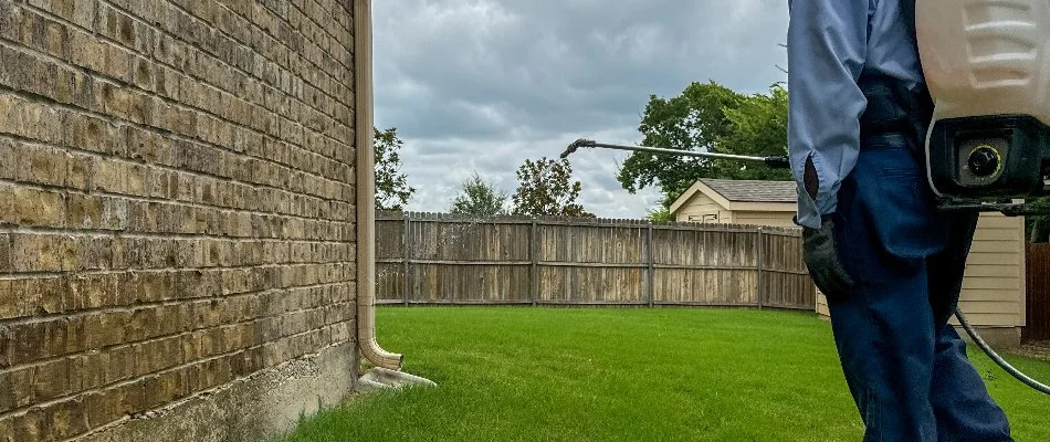 Pest control technician applying a treatment to a home in Mansfield, TX.