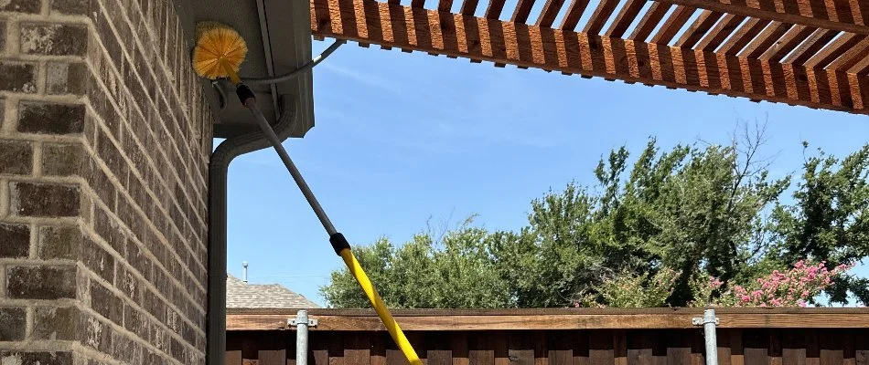 A pole with a pest duster for a home's eaves in Lancaster, TX.