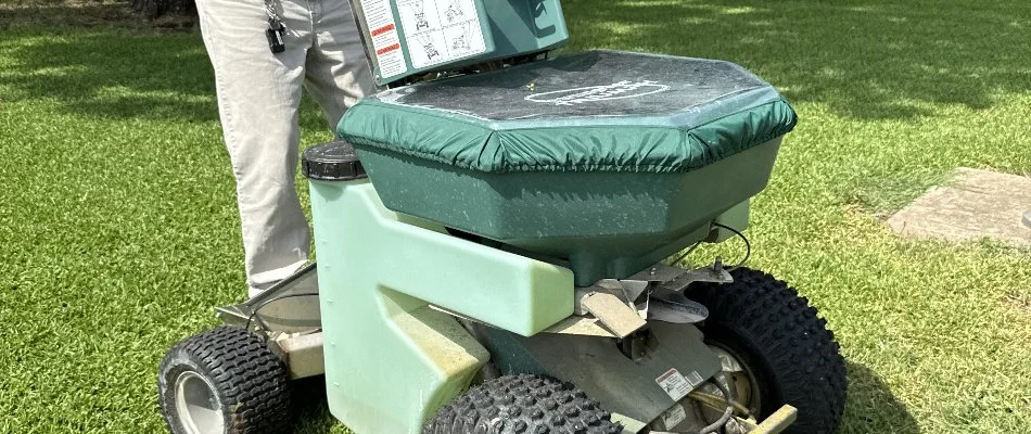 Spreader machine with granular fertilizer for a lawn in Dallas, TX.