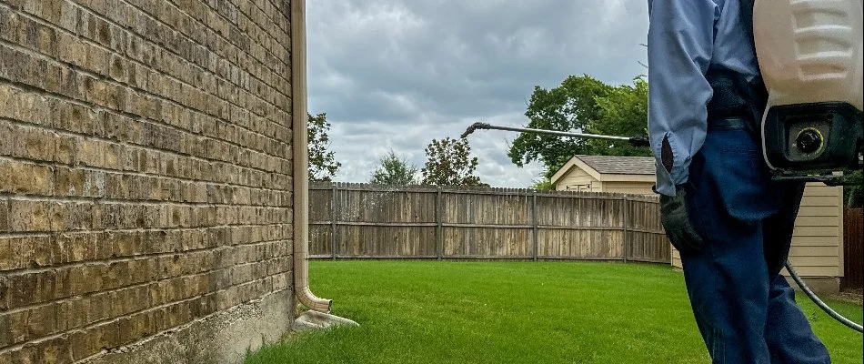 Tech applying a pest treatment to a building in Frisco, TX.