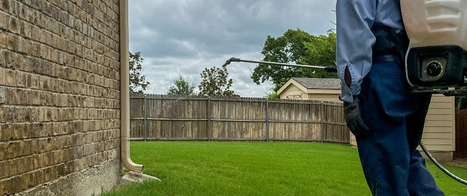 Wall of a house in Venus, TX, being sprayed with perimeter pest control treatment.