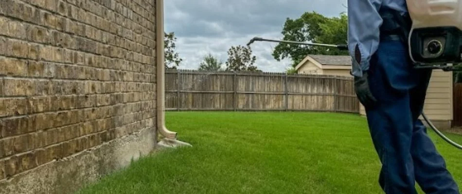 Worker applying a perimeter pest control treatment to a lawn in North Richland Hills, TX.