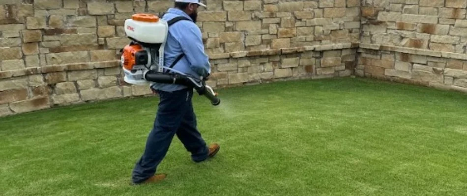 Worker applying a pest control treatment to a lawn in Waxahachie, TX.