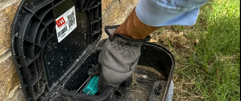 A worker in DeSoto, TX, replacing bait in a pest device.