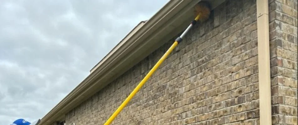 Worker using a yellow pole during a pest control service in Grand Prairie, TX.